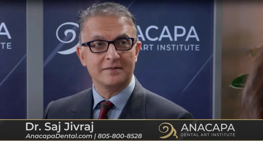 Professional man in suit and glasses at Anacapa Dental Art Institute event with branded backdrop