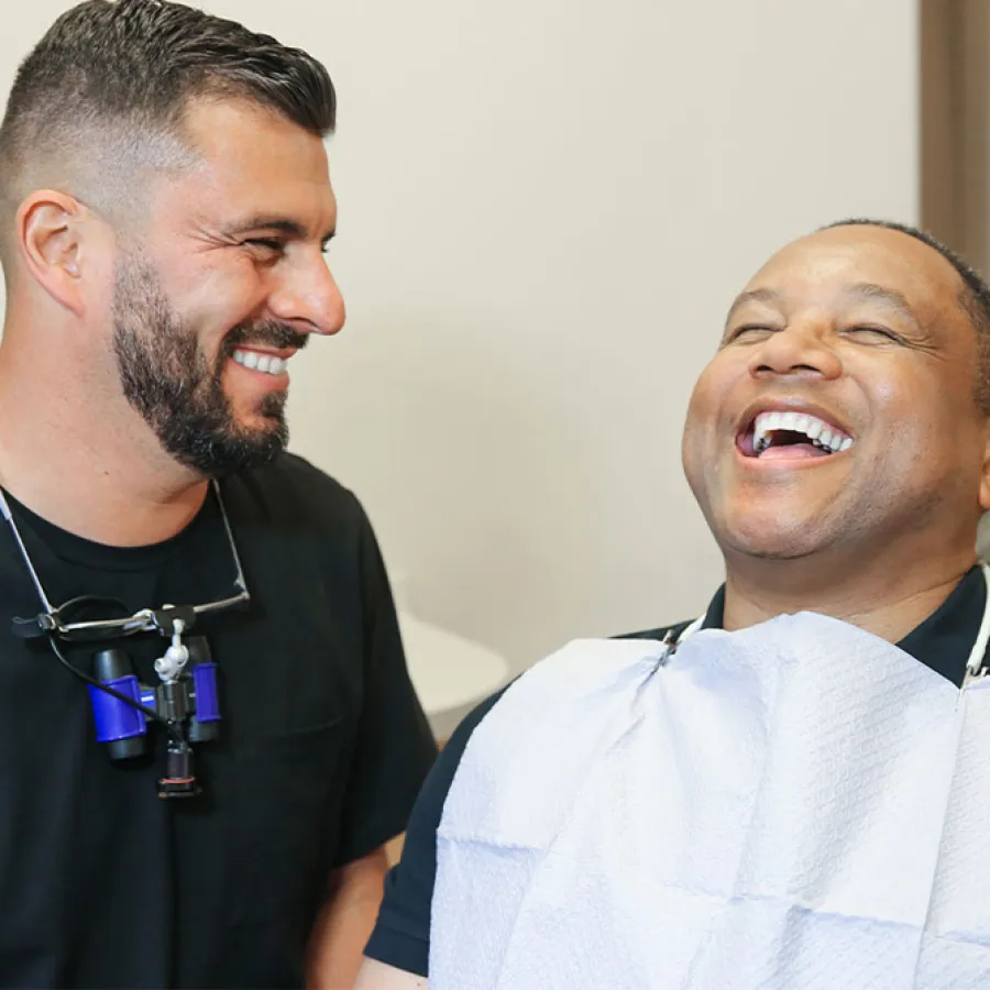 A dentist and patient share a joyful moment during a dental check-up, highlighting patient care.