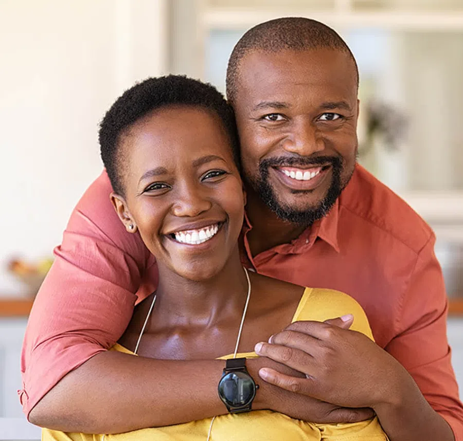 Happy smiling African American couple embracing in bright modern home, showing affection and joy