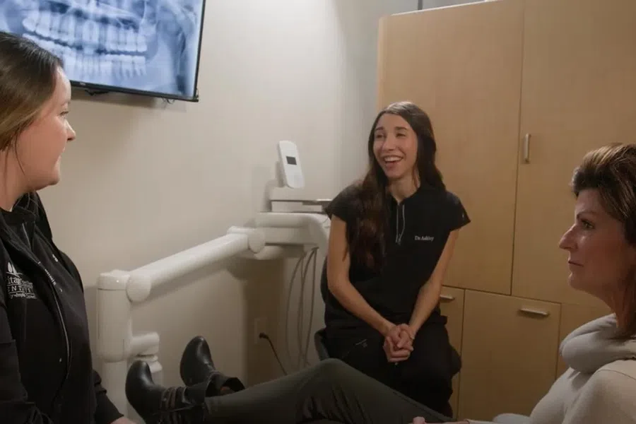 Dental consultation with smiling patients and professionals in a modern clinic environment.