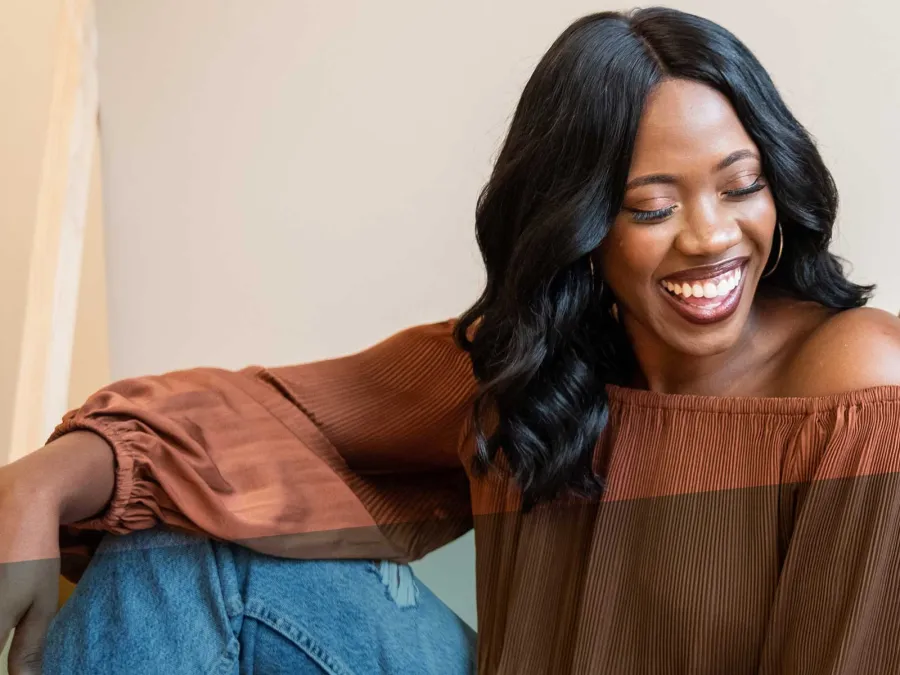 a woman smiling and leaning on a wall