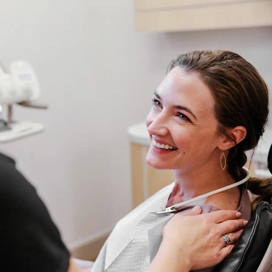 Smiling woman at dental appointment, feeling relaxed and happy in a modern clinic.