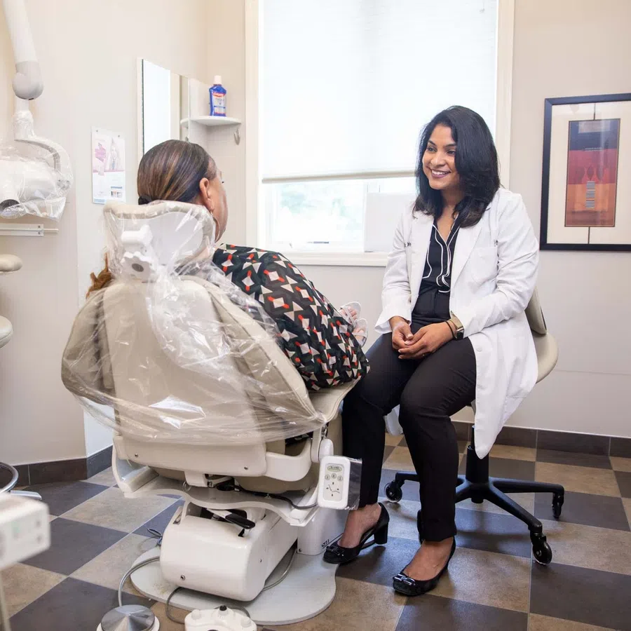 Dentist consulting a smiling patient in a modern dental clinic with bright natural light and clean surroundings