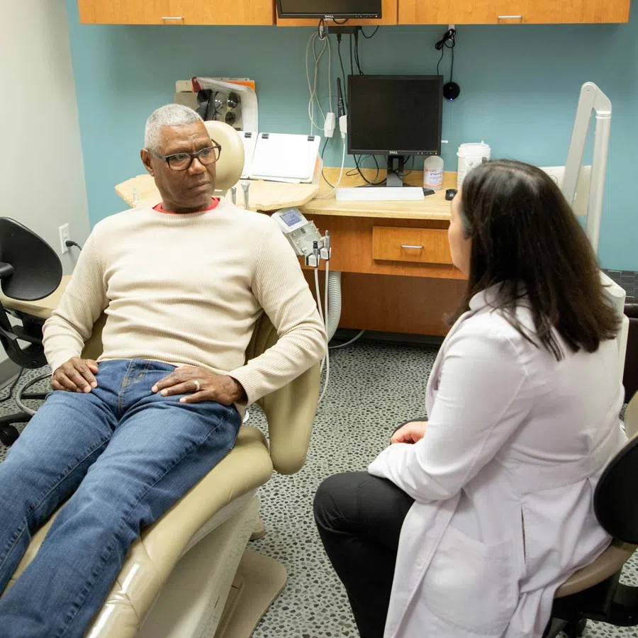 Elderly man in casual clothes consulting with a female doctor in a medical office setting.