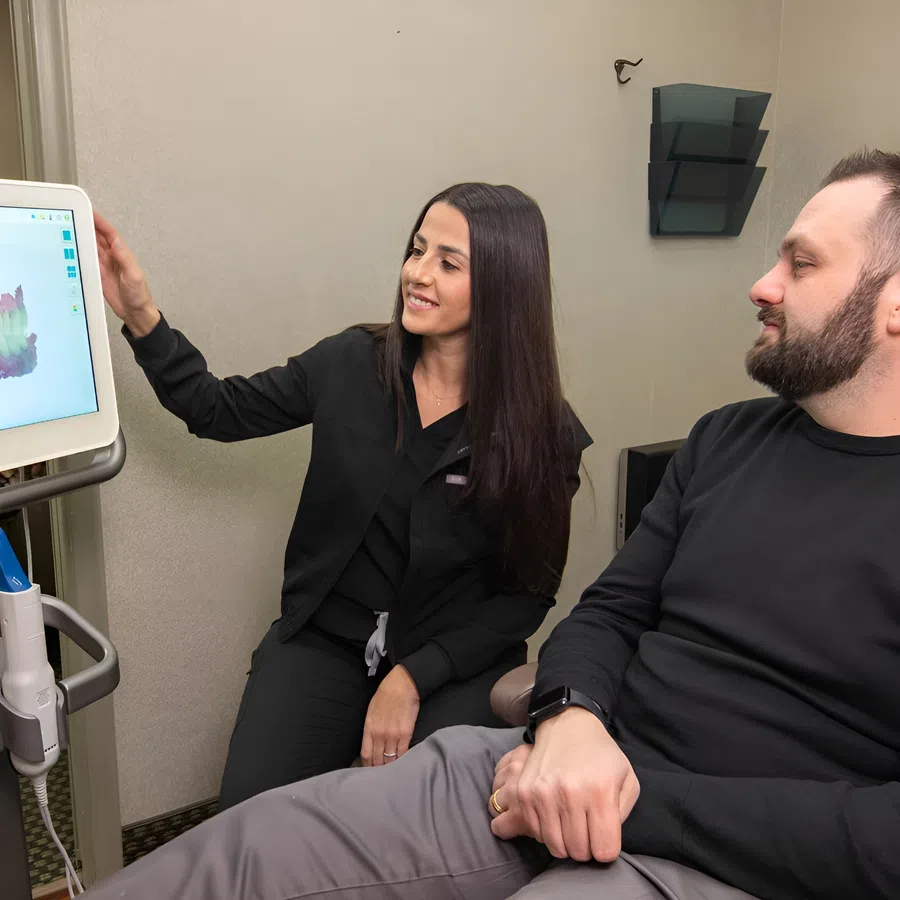 Female dental professional showing 3D dental imaging to male patient during consultation in clinic