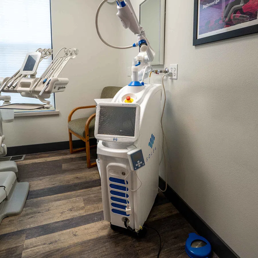 Soley dental laser machine with control panel and articulated arm in a modern clinic room with wooden floors.