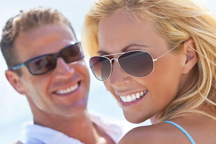 Smiling man and woman wearing sunglasses enjoying sunny outdoor day together.