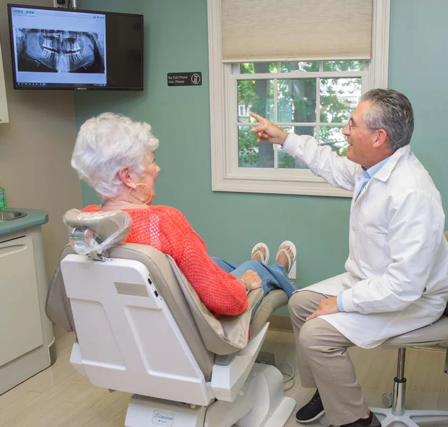 Dentist explaining dental X-ray results to senior woman patient in dental office consultation.