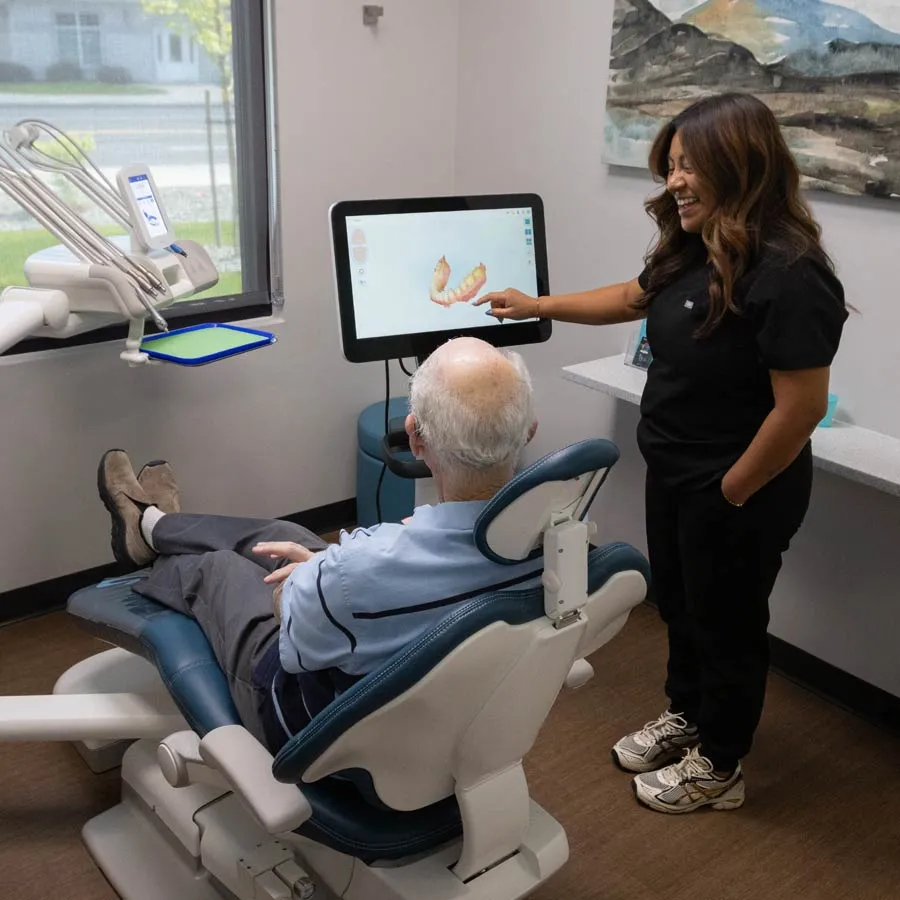Dentist showing older patient a 3D dental scan on screen in modern dental clinic setting