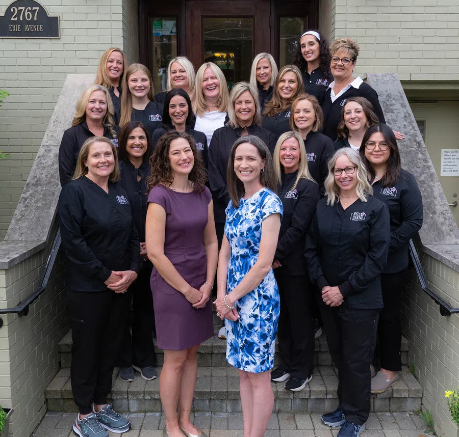 Group of 20 women standing on steps outside building at 2767 Erie Avenue, smiling and posing for photo
