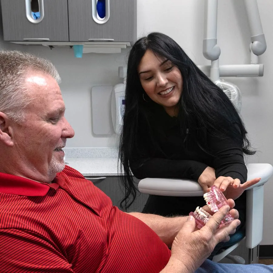 Dentist explaining dental care using a teeth model to a patient in a dental clinic