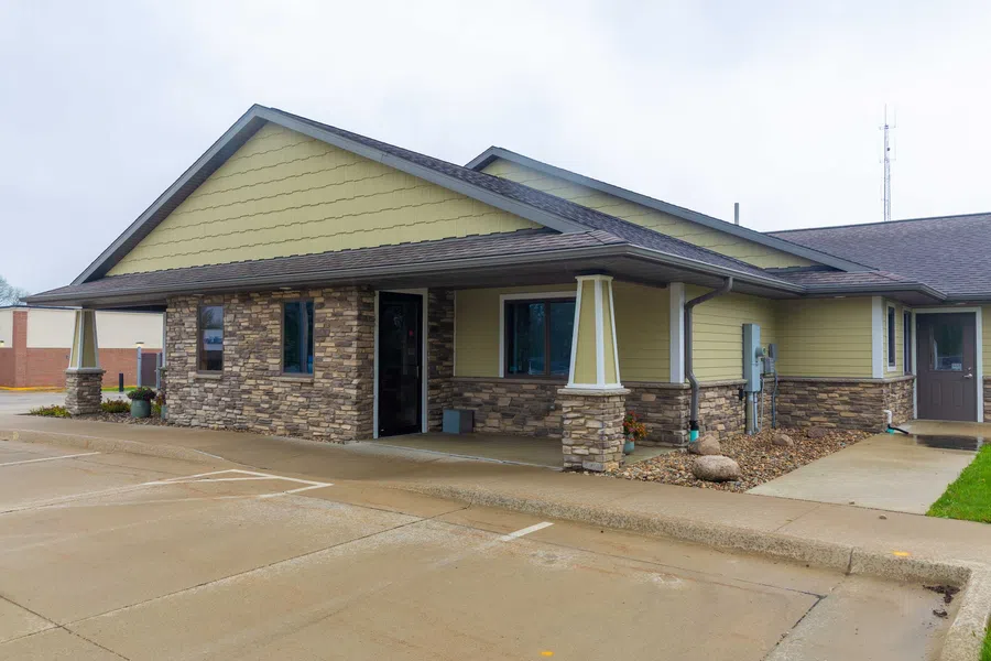 Modern single-story building with stone and yellow siding exterior and covered entrance on cloudy day