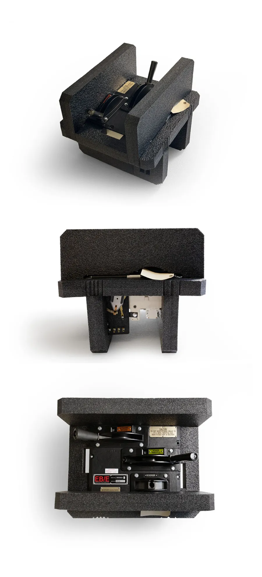 Black mechanical control lever unit encased in protective foam from multiple angles on white background