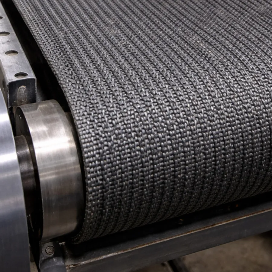Close-up of industrial conveyor belt with textured black rubber surface and metal rollers.