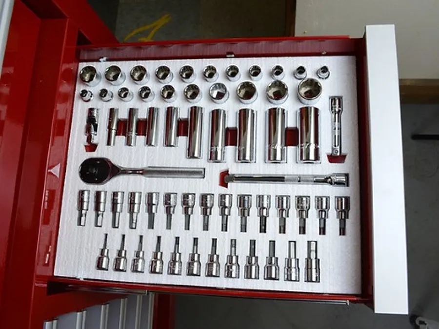 Organized red toolbox drawer with various polished chrome socket wrenches and a ratchet handle.