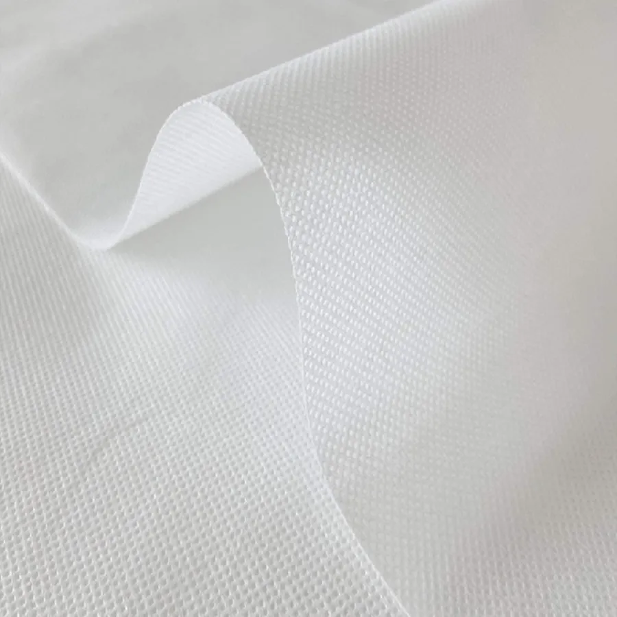 Close-up of white textured fabric with visible mesh pattern and soft folds creating depth and shadow.
