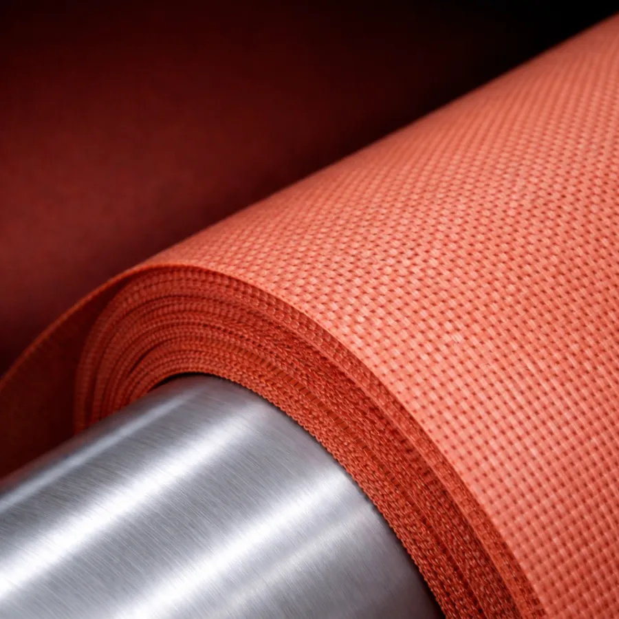 Close-up of tightly rolled textured orange fabric around a shiny metal cylinder with a dark background
