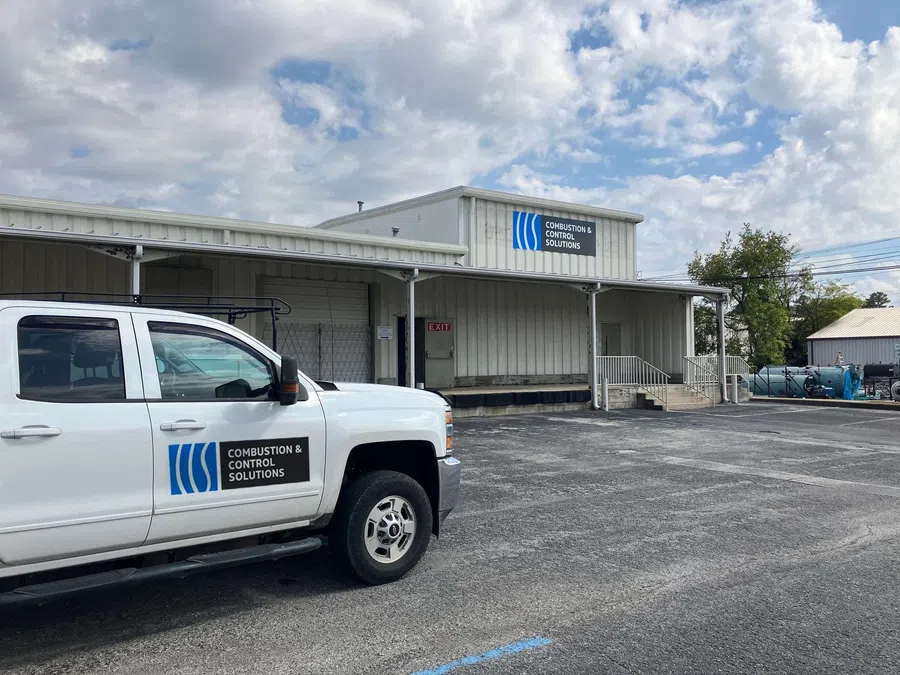 White truck and building with Combustion & Control Solutions signage under partly cloudy sky