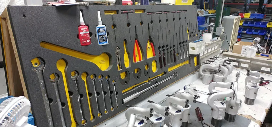 Organized tool panel with wrenches, adhesives, and pneumatic tools in a workshop setting.