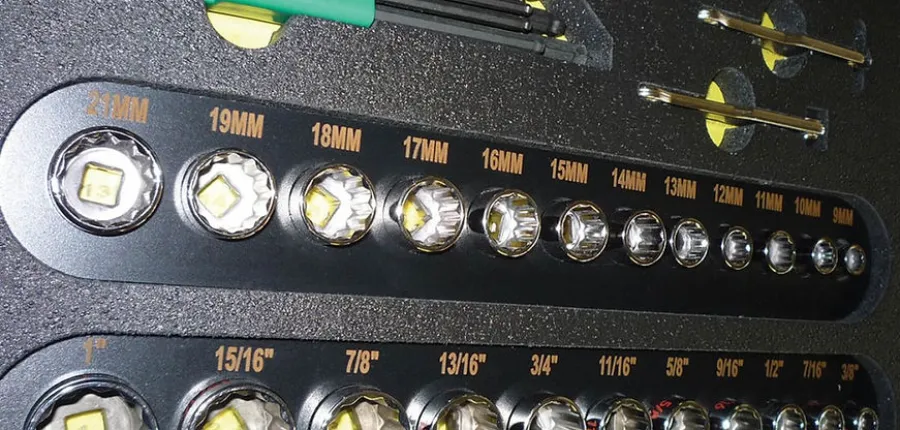 Close-up of various sized socket wrench heads organized in a tool kit with labeled measurements.