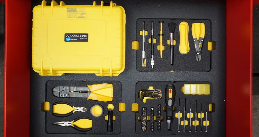 Yellow outdoor case and organized yellow-handled tools in custom foam inserts inside a red drawer.