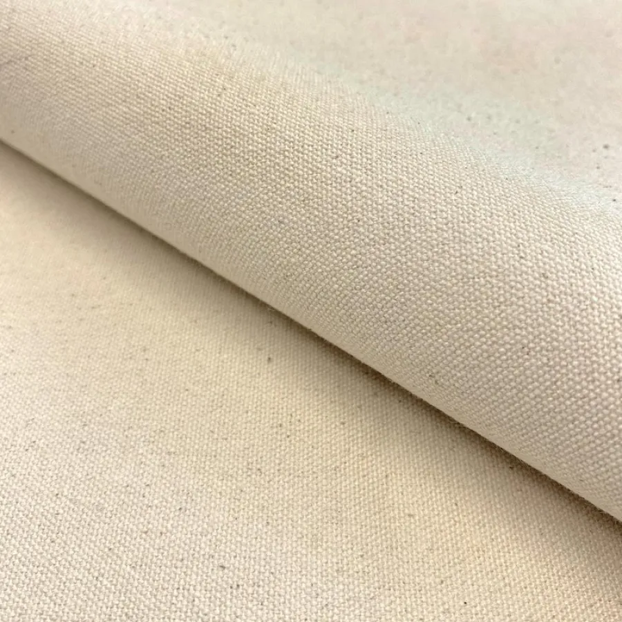 Close-up of natural beige cotton canvas fabric with visible weave texture rolled over flat surface