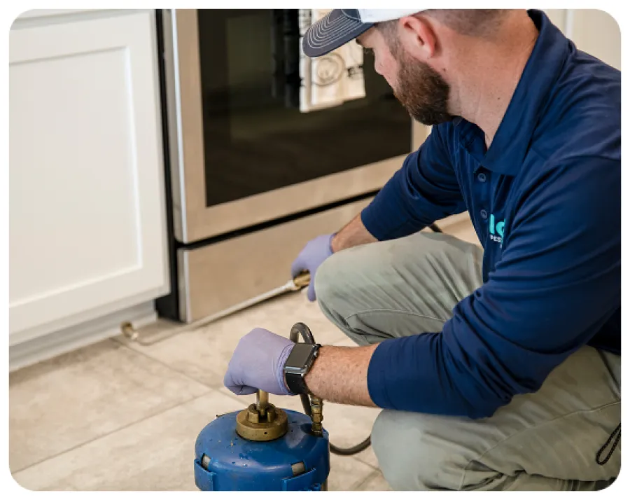 Technician repairing a refrigerator with tools in a modern kitchen setting.