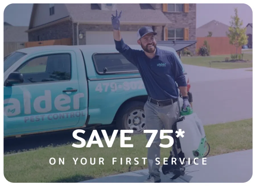 Smiling pest control worker holding equipment next to Alder Pest Control truck offering 75% off first service.