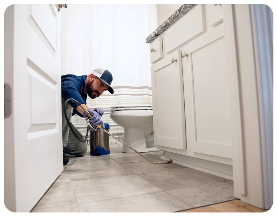 Professional plumber repairing pipes in a bright, modern bathroom setting.