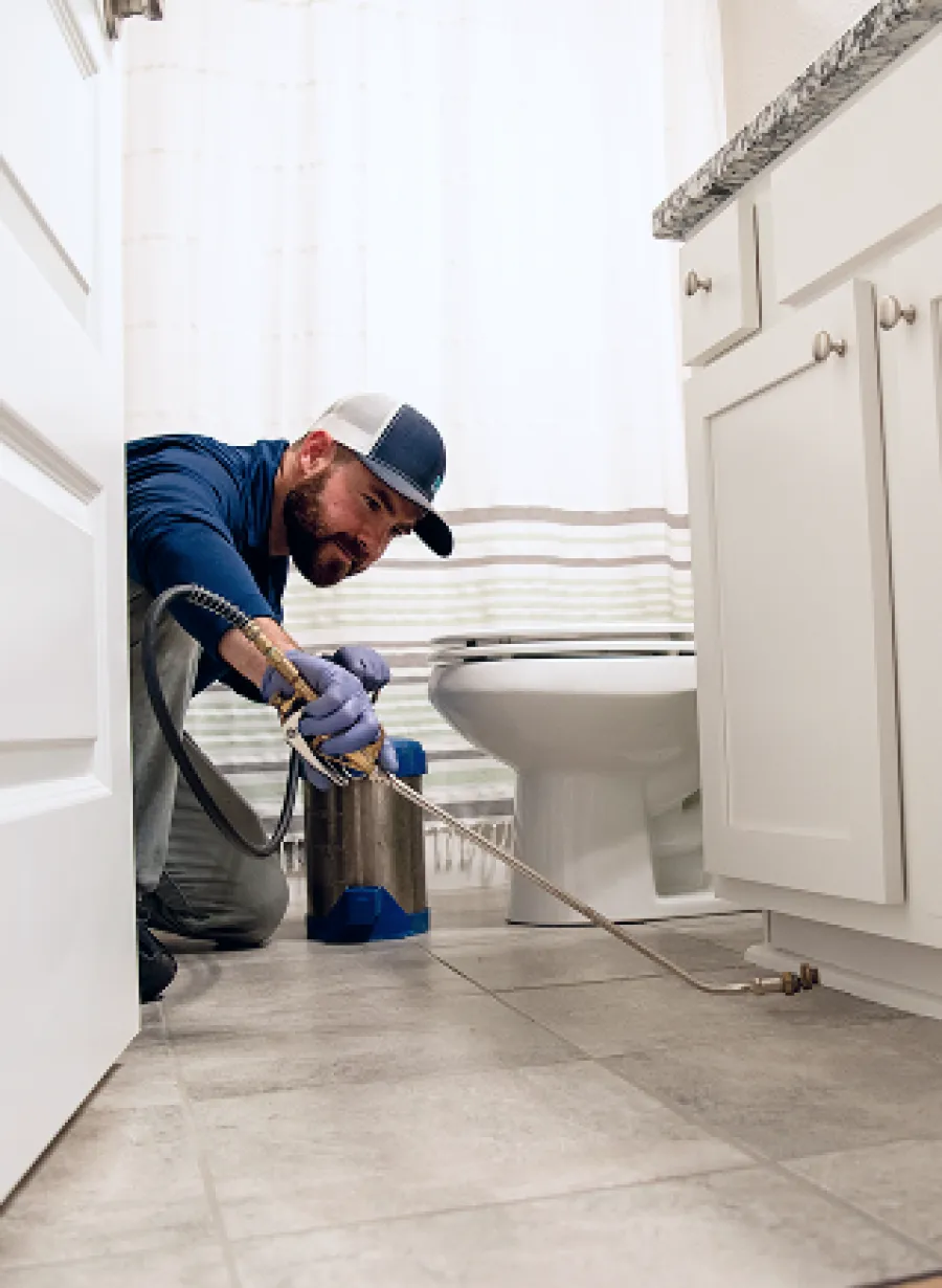 Professional plumber repairing pipes in a bright, modern bathroom setting.