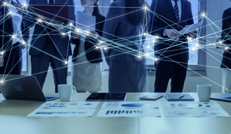 Business team standing behind a desk with digital network connections and charts symbolizing collaboration and data exchange.