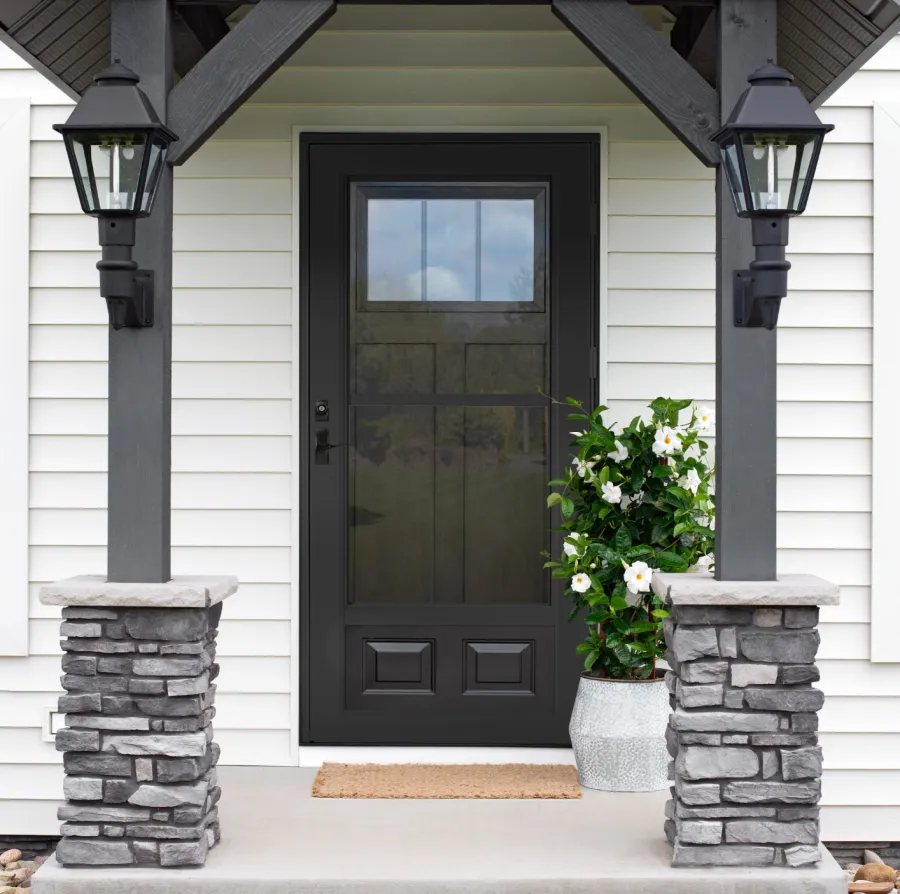 a house with a black door and a stone patio with a stone fireplace