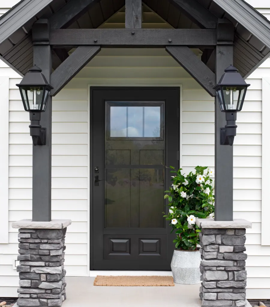 a house with a black door and a stone patio with a stone fireplace