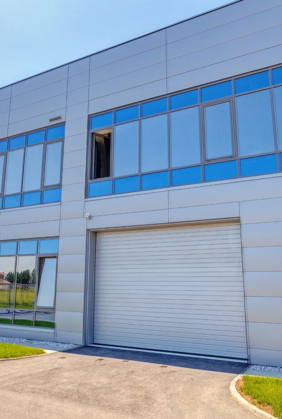 Modern commercial building with large glass windows and metal exterior panels under a clear blue sky.
