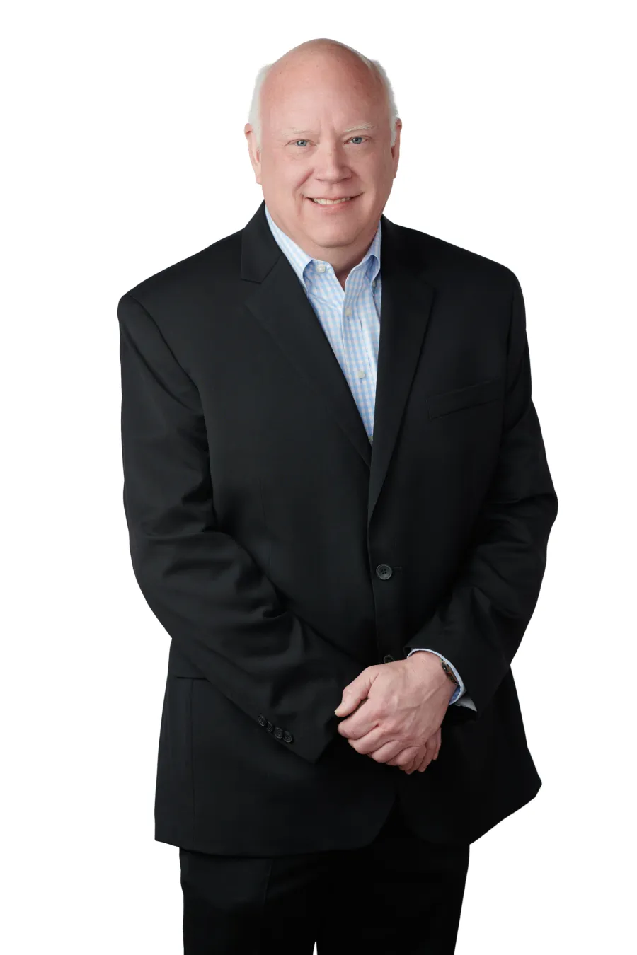 Smiling middle-aged man in a black suit and light blue shirt standing against a white background.