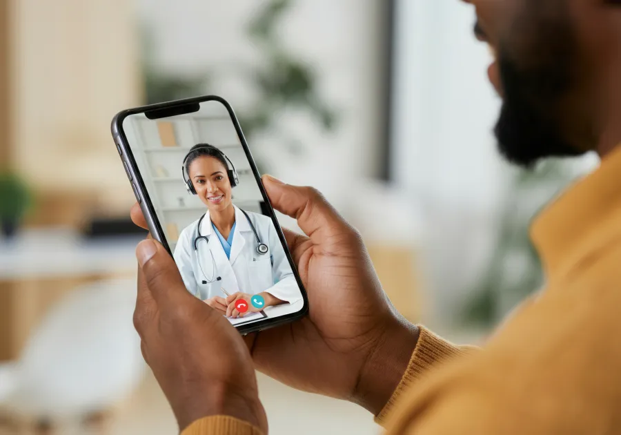 Person holding a smartphone showing a doctor during a telehealth consultation.