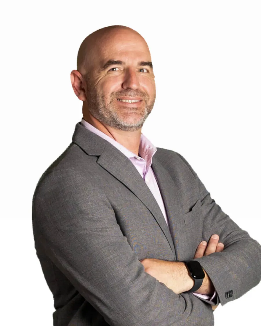 Confident bald man in gray suit with crossed arms smiling against white background