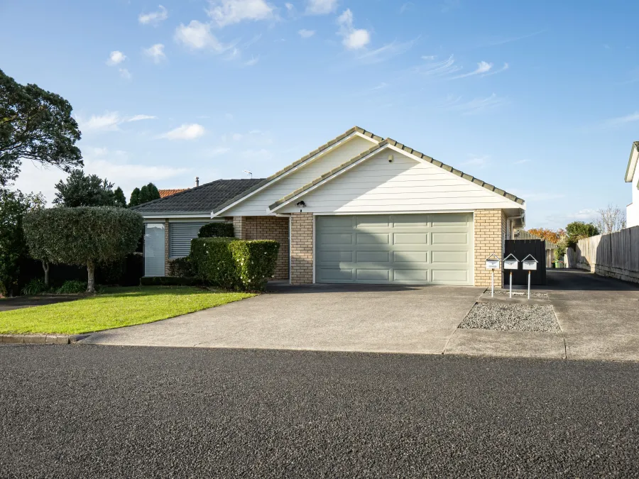 A charming suburban home with a green garage, manicured lawn, and modern mailbox on a sunny day.