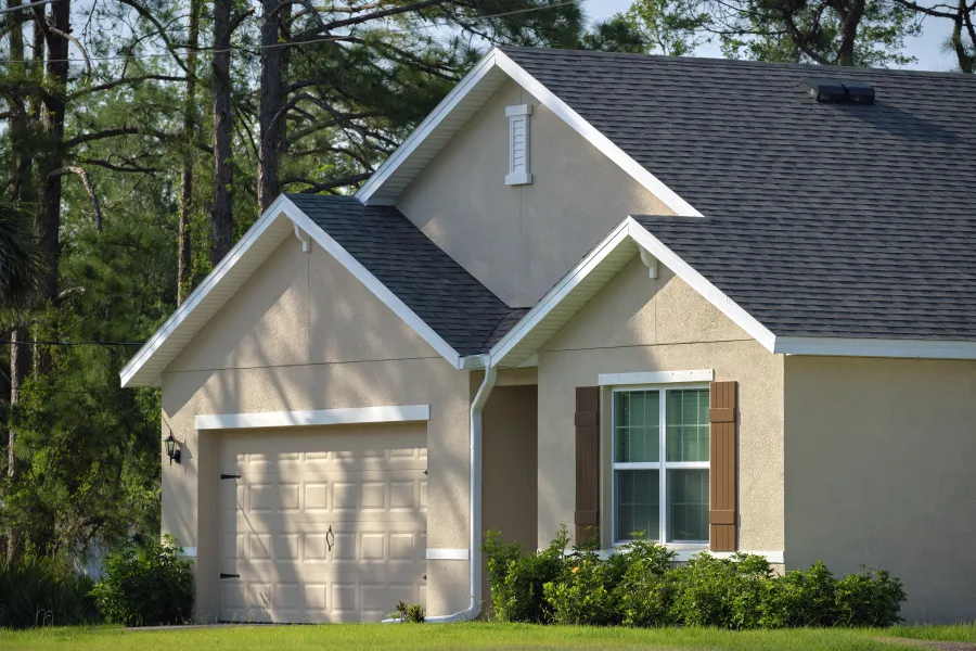 Close-up of a modern suburban home featuring a beige facade and manicured landscaping.