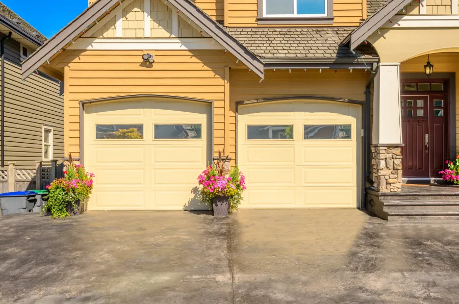 a house with garages and a patio with flowers in front