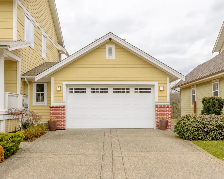 Charming yellow house with a spacious two-car garage and well-maintained driveway.