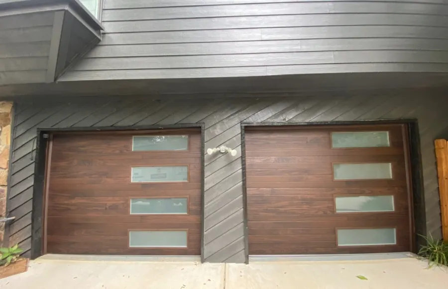 Stylish modern double garage doors with wooden finish and glass panels on a sleek home exterior.