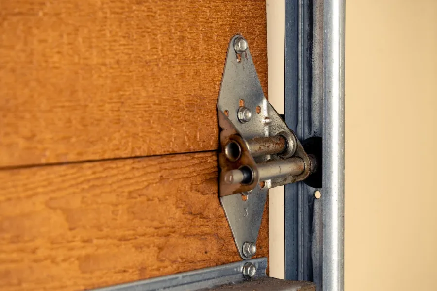 Close-up of a metal hinge securely attaching a wooden panel to a metal frame in a door.