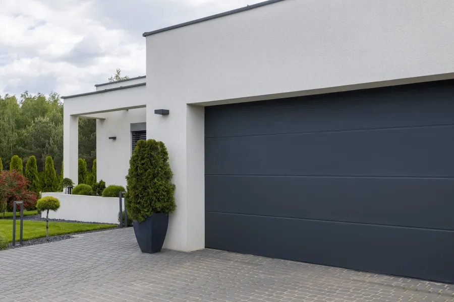Modern home exterior with sleek garage door, manicured garden, and contemporary architectural design.