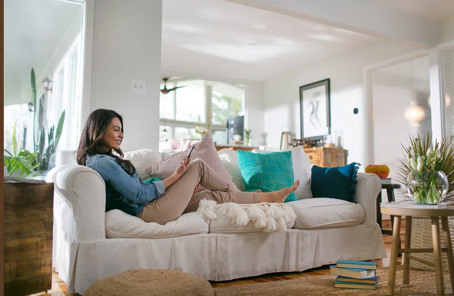 Young woman relaxing on a couch without a blanket due to a comfortable room temperature.