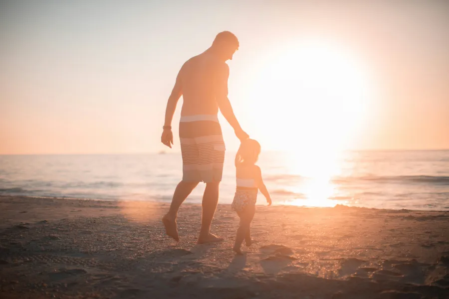 a woman and a child walking on a beach