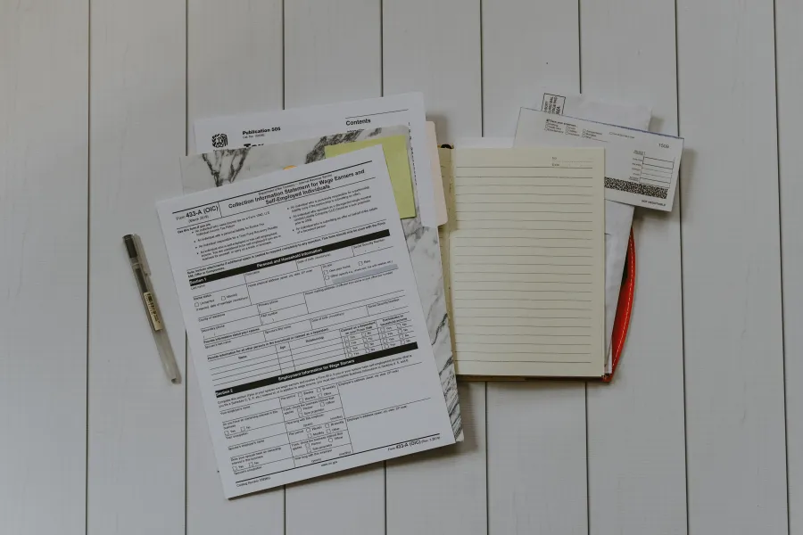 a white board with papers and a pen on it