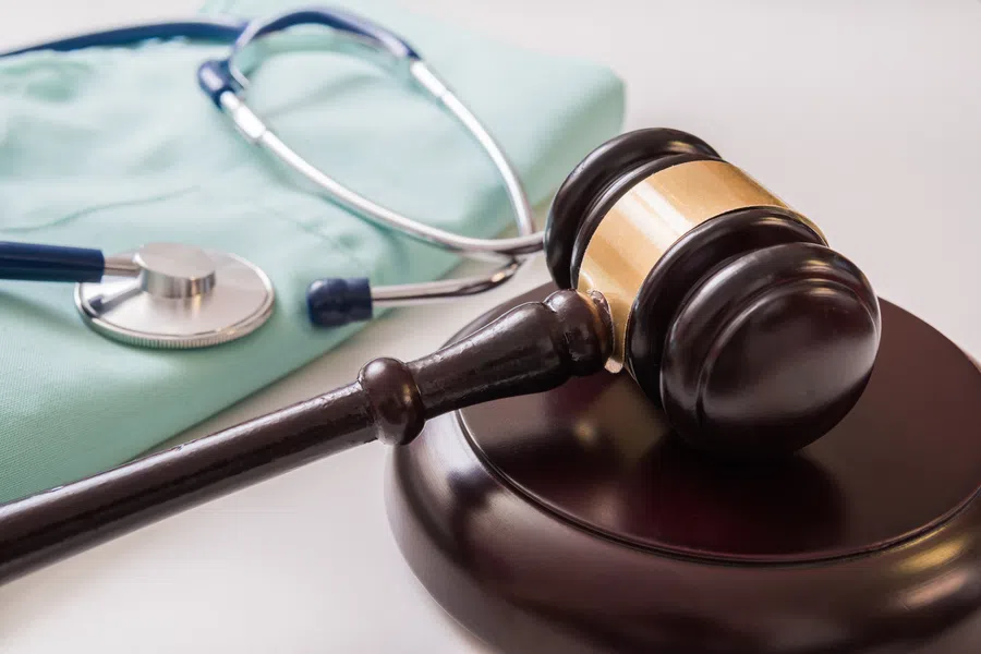 Judge's gavel with stethoscope and medical scrubs symbolizing medical law and healthcare justice.