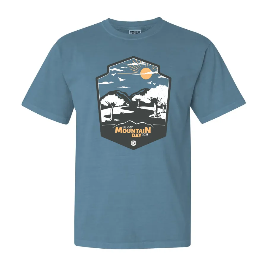 Blue t-shirt with a Berry Mountain Day 2025 design featuring trees, mountains, sun, and birds.