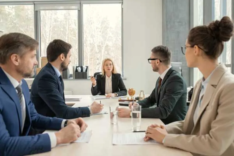 Business professionals having a meeting in a modern office with large windows and natural light.